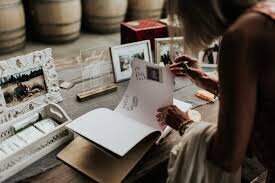 a woman signs the photo guest book at a wedding after using the open air photo booth