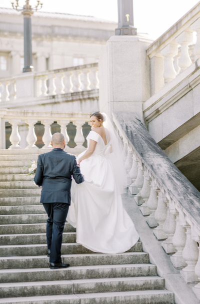 Couple walks up stone stairs together for wedding
