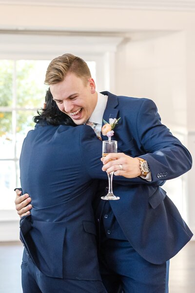 Phoenix-Wedding-Photographer-and-Videographer-Groom-Hugging-and_Smiling-with-Champagne-DolyWed-1670