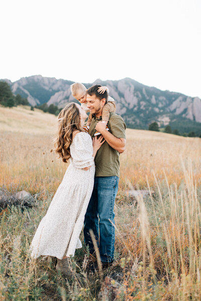 parents kissing while holding their son and daughter on dad's shoulders