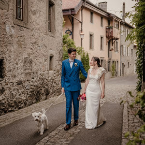 Séance couple dans un village au bord du Lac Léman en Suisse, en promenade avec leur chien – un moment complice et naturel capté par un duo photographe vidéaste