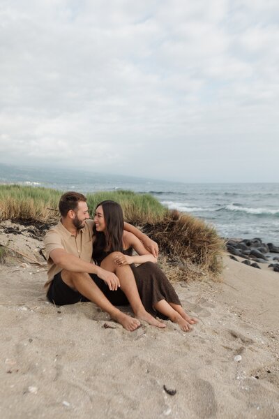 couple sitting on beach in hawaii