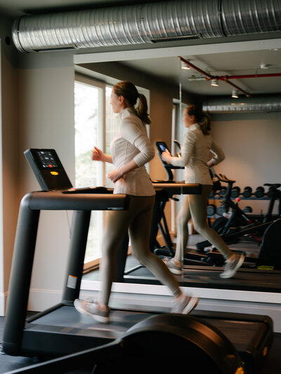 Junge Frau joggt auf dem Laufband im Fitnessraum des Hotels the breeze.