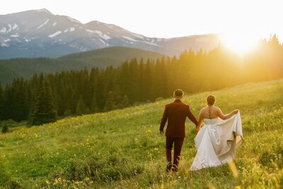 Bride and groom walk along mountainside during elopement day sunset.