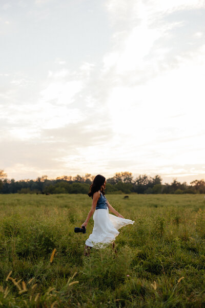 woman holding a camera while roaming through an open field
