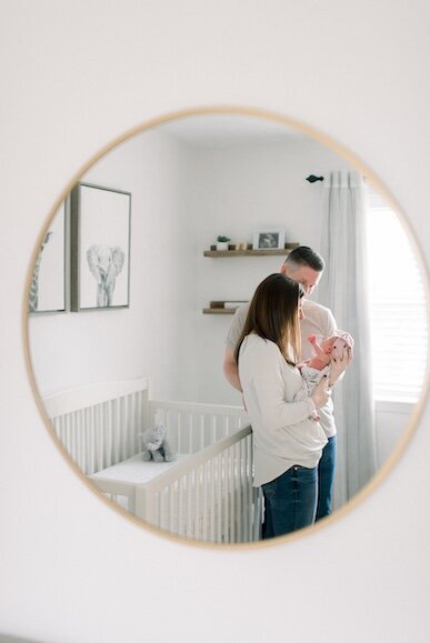 mom day and newborn baby girl reflected in nursery mirror