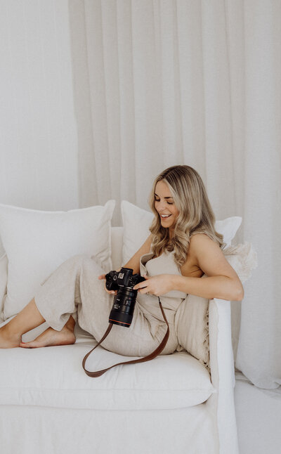 Lucy jane, a professional photographer holding her camera and looking through photographs on her camera in her photography studio