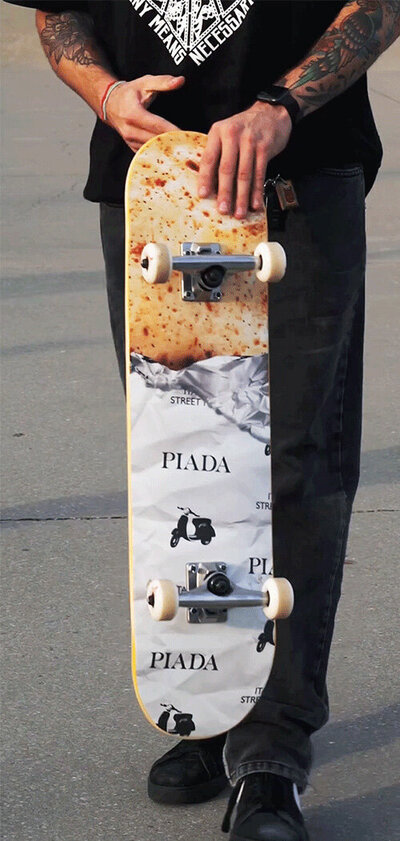 A skateboard deck  with printed vinyl applied to look like a half unwrapped Piada (Italian street wrap)