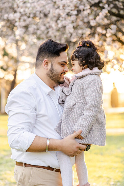 Indian dad holding daughter playing whilst having family portraits taken during sunset.