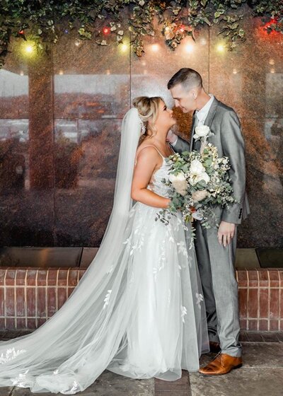 A bride and groom embracing under warm ambient lights in an evening wedding setting, captured in a romantic and softly lit portrait by a UK wedding photographer.