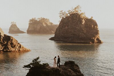 Eloping couple standing on rock overlooking an Oregon Coast beach