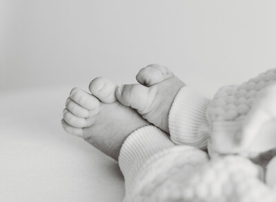 Black and white close-up of newborn baby feet in a cozy knit onesie, captured during a natural Kansas City newborn photography session.