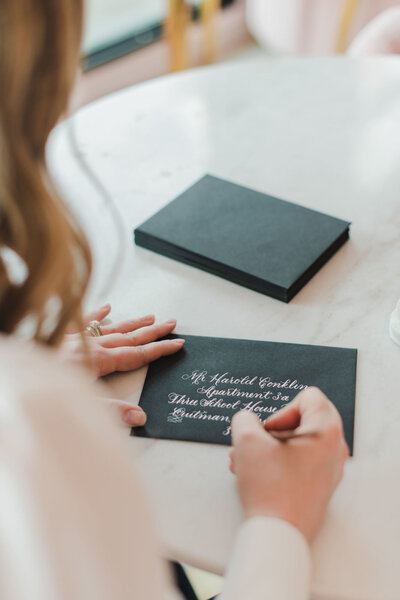 A woman writing an address on a wedding envelope in calligraphy