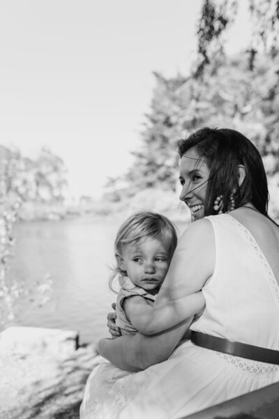 Family Photographer,  mother holds baby girl at the lake
