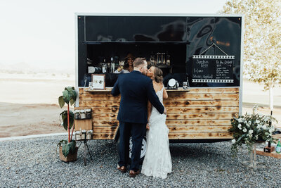 bride and groom standing in front of beer cart