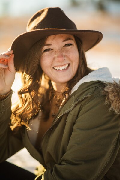 Valerie smiling while holding her hat