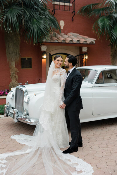 Bride and groom veil shot romantic nuzzle white tux jacket long cathedral veil at the pelican club jupiter south florida white rose boutonniere