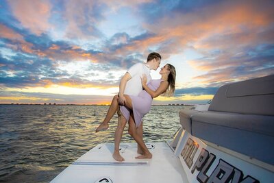 romantic wide angle of couple on the bow of a boat at sunset in Sarasota Bay right after he proposed