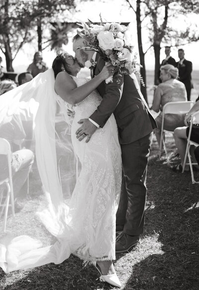 Agar's corner wedding in Saskatoon. Couple sharing a kiss down the aisle.