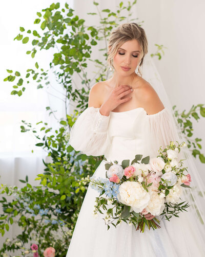 Ottawa wedding photography of a bride in strapless ballgown looking down at her pink, white and blue bouquet.  Captured by JEMMAN Photography