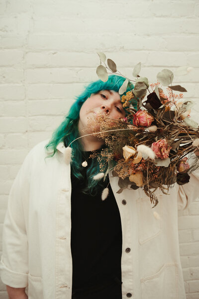 portrait of photographer holding white flowers and smiling