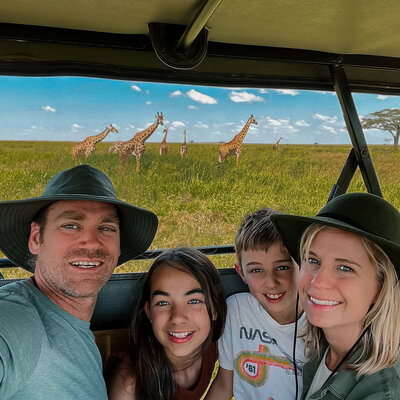 Family selfie on safari with giraffes behind