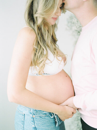 Close up of mom and dad cradling new baby bump, captured by Edmonton maternity photographer, Kahla Kristen