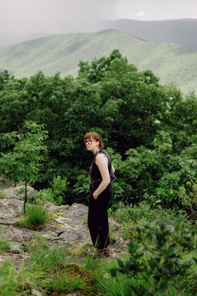 Bride holding a wildflower bouquet and gazing into the distance during her Virginia mountaintop elopement, captured in soft, editorial light with a film-inspired look.

