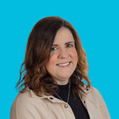 woman therapist at move forward with dark hair with black shirt and cream shacket on blue background