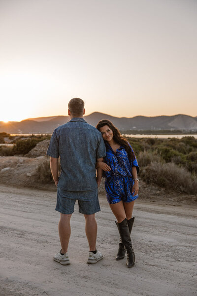 A woman is cuddling the arm of her man during a love shoot on ibiza at sunset.