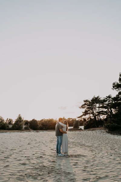 Vrouw en man geven elkaar een kus op het wekeromse zand