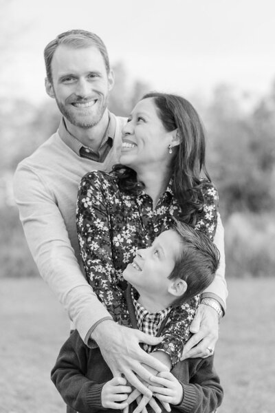 mom and son looking at dad with big smiles during their fall mini session in Sterling, Virginia