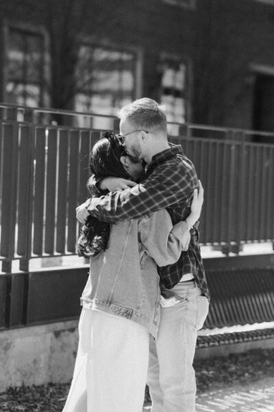 Cinematic wide shot of the couple embracing on the summit, with soft focus and natural light.
