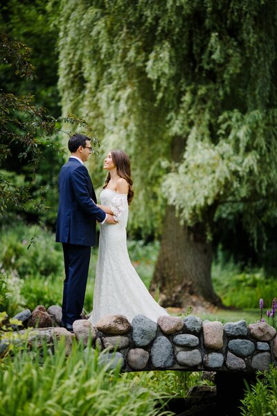 Outdoor portrait of bride and groom in a scenic landscape with a large tree in the background