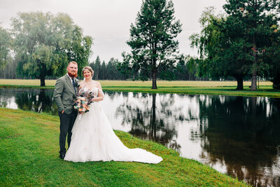 Portrait of bride and groom by pond at The Barn at Finley Point in Polson, Montana