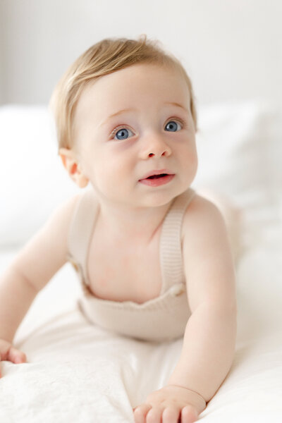 Tampa baby 6 month portrait: baby peacefully lying on crisp white bedding in a luxury studio session