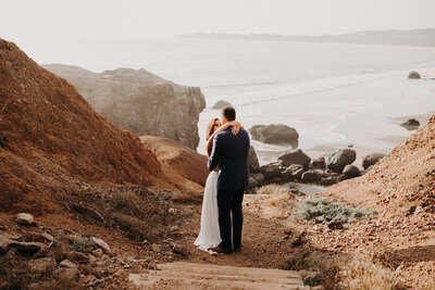 bride and groom embracing at the opening of a beach view