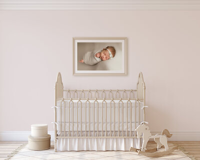 A newborn nursery with a framed picture of a baby girl on the wall.