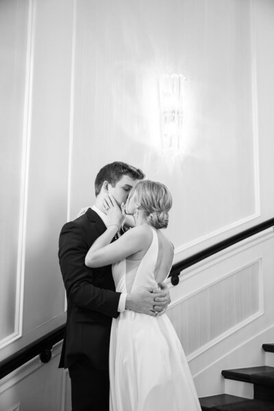 black and white image of bride and groom kissing on stairs