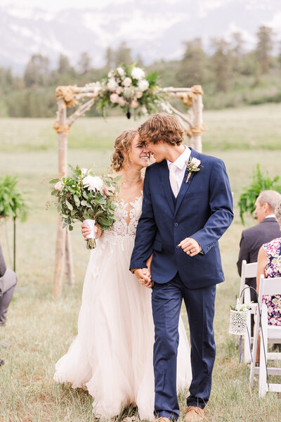 A joyful couple walking down the aisle after their wedding at Top of the Pines in Ridgway, CO, radiating love and celebration