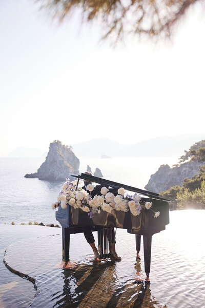 baby grand piano with floral arrangement with Amalfi Coastline view