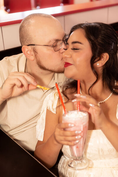 Couple sharing a milkshake during their save-the-date session at a diner in Utah, captured by Lamblight Photography