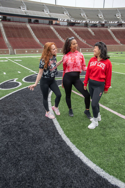 Three models wearing various college game day apparel on football field