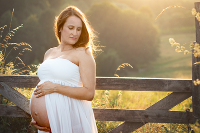 Pregnant mum holds her bump whilst posing for a maternity shoot