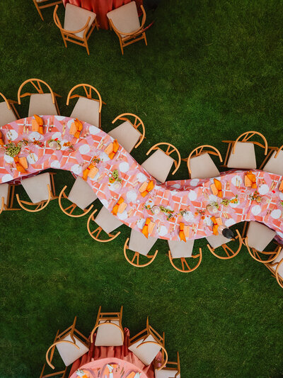 A long wedding table draped in soft linen, adorned with elegant tapered candles and lush floral arrangements—crafted for a refined and romantic celebration.