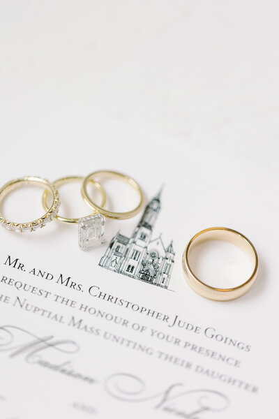 Wedding rings on top of invitation with illustration of guadalupe cathedral in downtown dallas by Kortney Boyett Photography, Dallas wedding photographer