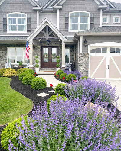 a house with beautiful plants lining the driveway