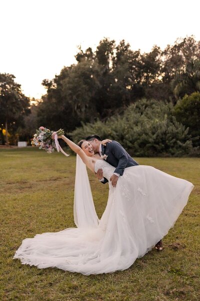 Groom dipping bride in field at Howey Mansion