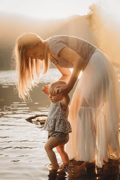 A mother holds her daughters hands while they stand in a gorgeous lake in Canandaigua, NY