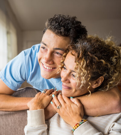 Teenage son hugs middle aged mother